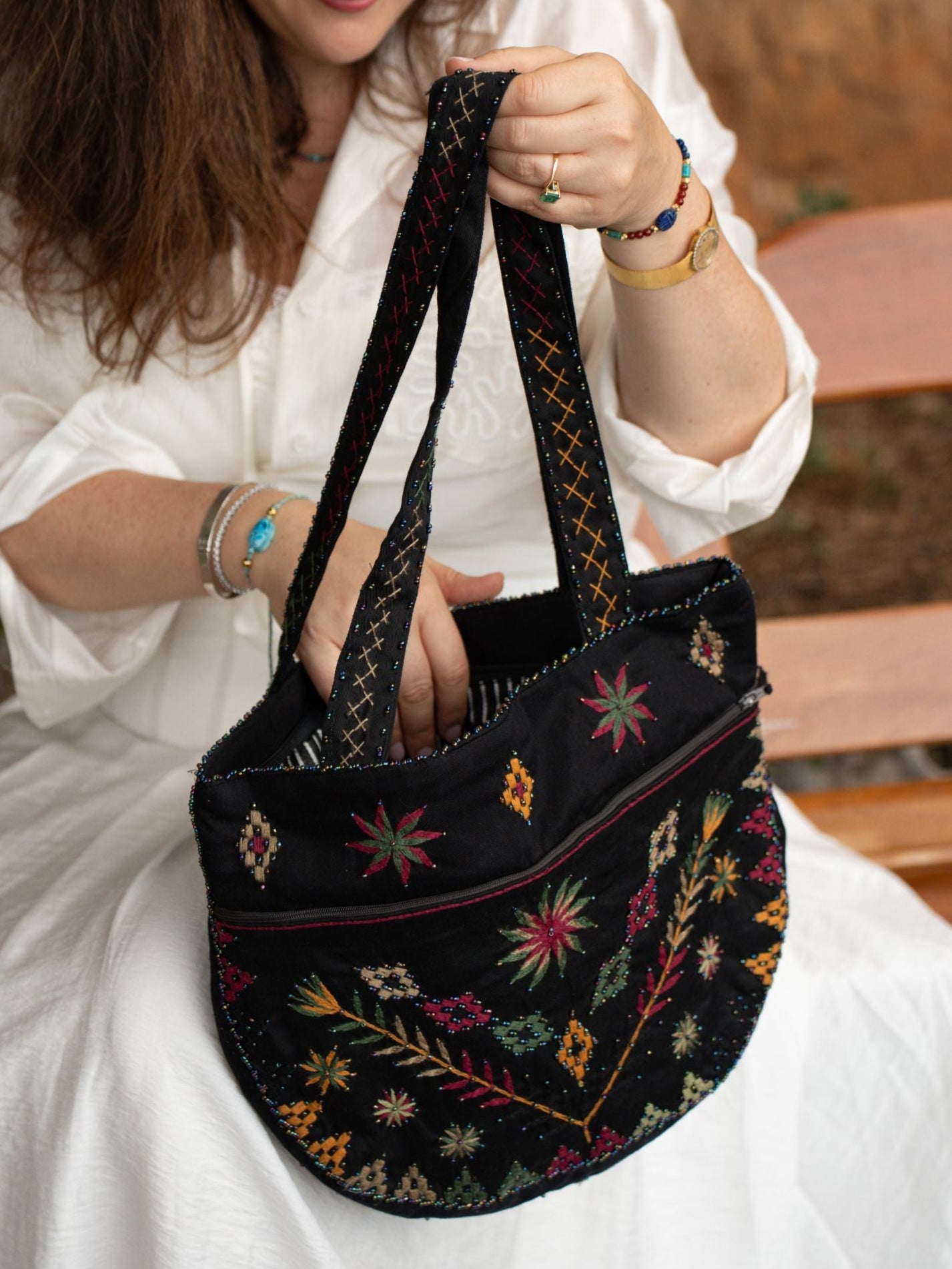 Détail du sac brodé Black Garden Nilazur avec motifs floraux en fil terracotta et vert sur toile noire, perles Miyuki délicates
