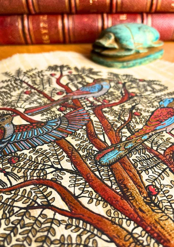 Papyrus arbre de vie égyptien posé sur un bureau avec livre et sculpture décorative
